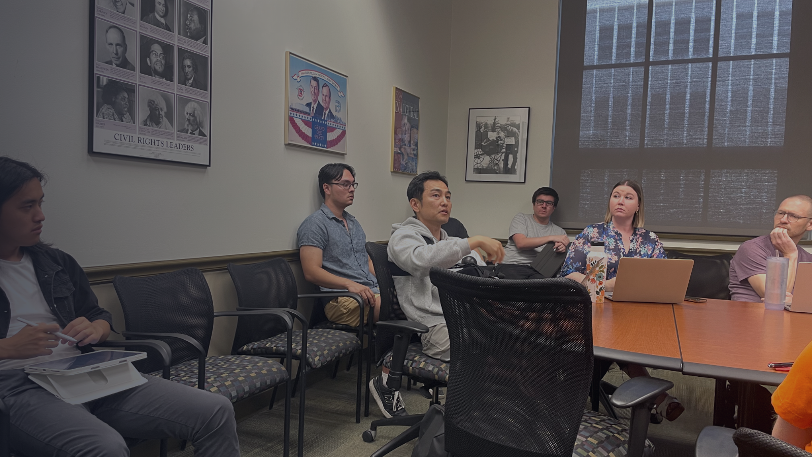 Students are seated in a laboratory meeting.