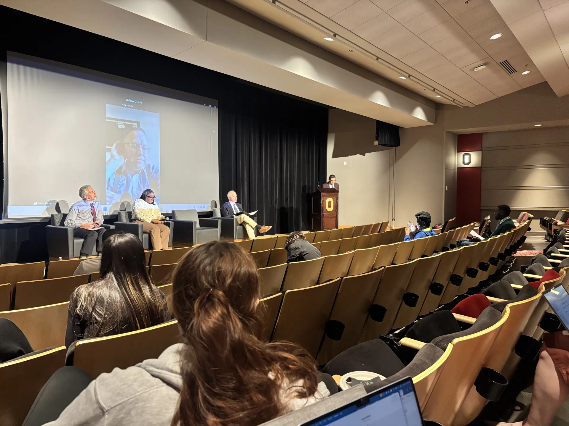 State Sen. Louis W. Blessing III speaks by Zoom during the Oct. 19 panel on effective lawmaking at the Ohio Union. State Rep. Latyna M. Humphrey and Center for Effective Lawmaking co-directors Craig Volden and Alan E. Wiseman are seated on stage
